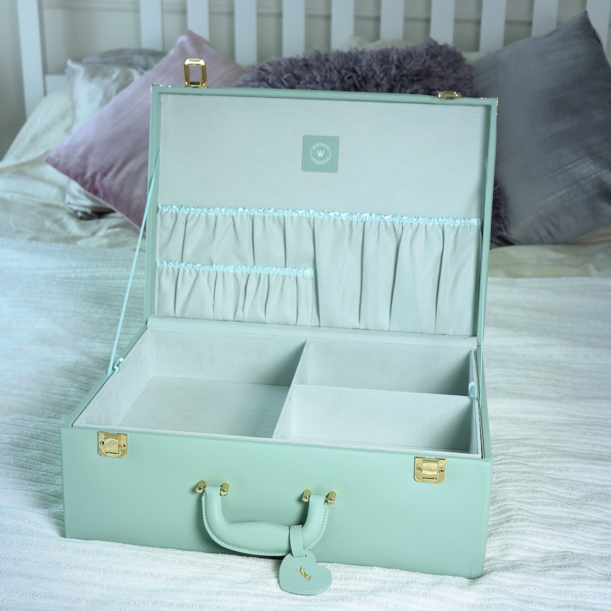 Mint green jewelry box on a bed with pillows