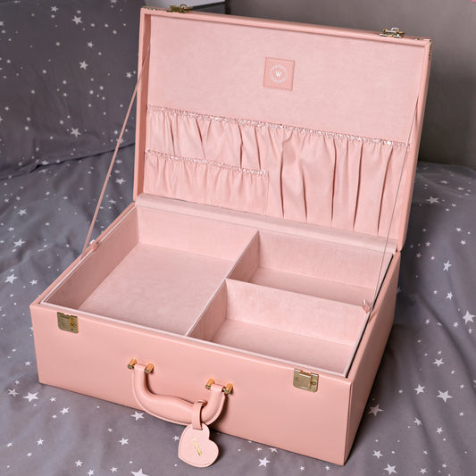 Pink jewelry box with compartments on a bed with star-patterned bedding