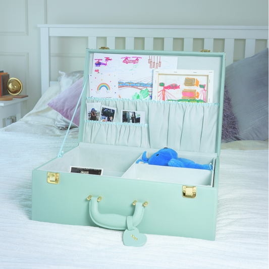 Mint green suitcase on a bed with children's drawings and toys inside, in a bedroom setting.