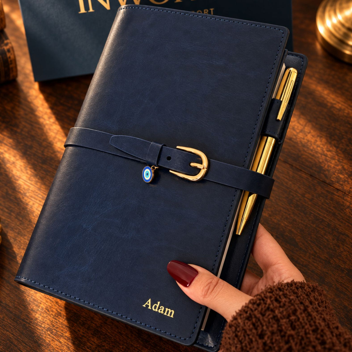 Navy blue Mémoire Journal by Inwords Gifting with a hardcover and gold embossed title, open to reveal lined pages inside.